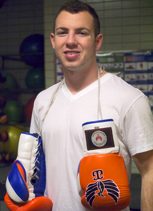 Danny goldberg holds a pair of boxing gloves that he designed for his company, Golden Gear. He used his background in Muay Thai as inspiration for Golden Gear.  