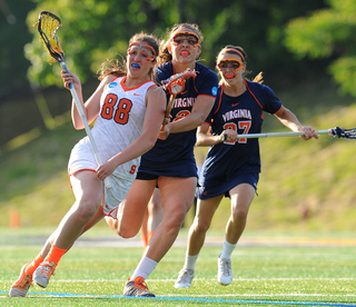 Sophomore midfielder Lisa Rogers runs upfield with two Cavaliers on her trail.