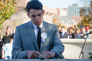 Bo Stewart, a senior with majors in economics, policy studies, political science, spanish language and literature and culture and a Remembrance Scholar, places a rose on the wall to commemorate Scott Marsh Cory, a Pan Am Flight 103 victim. 