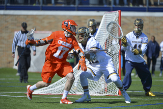 Syracuse attack Dylan Donahue staves off a UND defender as he moves toward the crease.