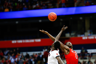 Louisville's Mangok Mathiang, left, and North Carolina State's Abdul-Malik Abu, right, take the opening tip at the start of the Sweet 16 round of the NCAA Tournament at the Syracuse Carrier Dome, March 27, 2015. 