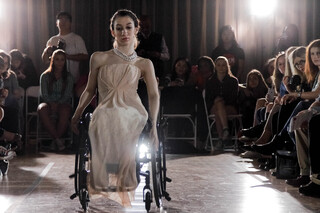 A model in a wheelchair makes her way on the runway during the Student Designs segment. She is wearing a design by Hannah Ballinger, co-student director of the show and a junior fashion design major. 