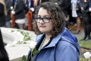 Nedda Sarshar holds a rose as others speak during the ceremony outside of the Hall of Languages.
