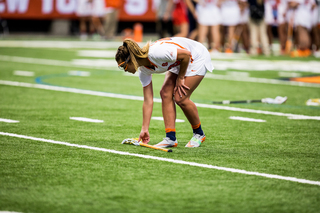 An Orange player bends down to pick up a stick. 